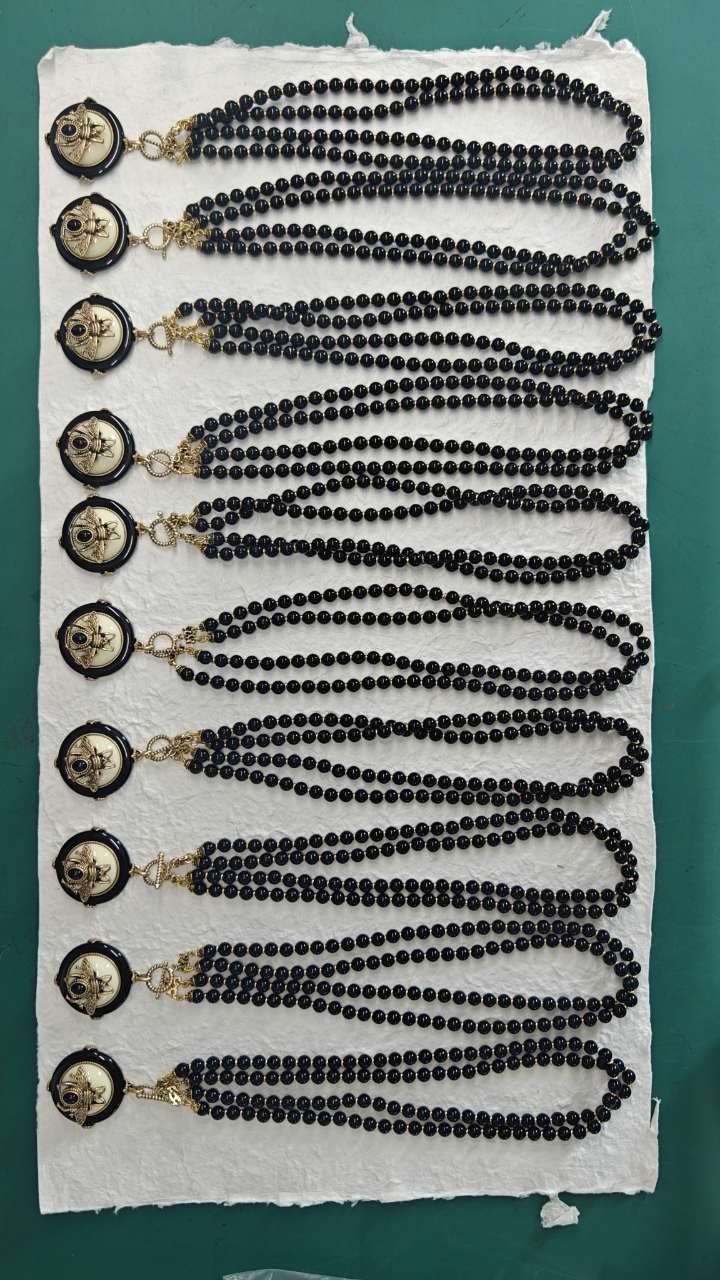 Multiple black bead medallion necklaces arranged during production