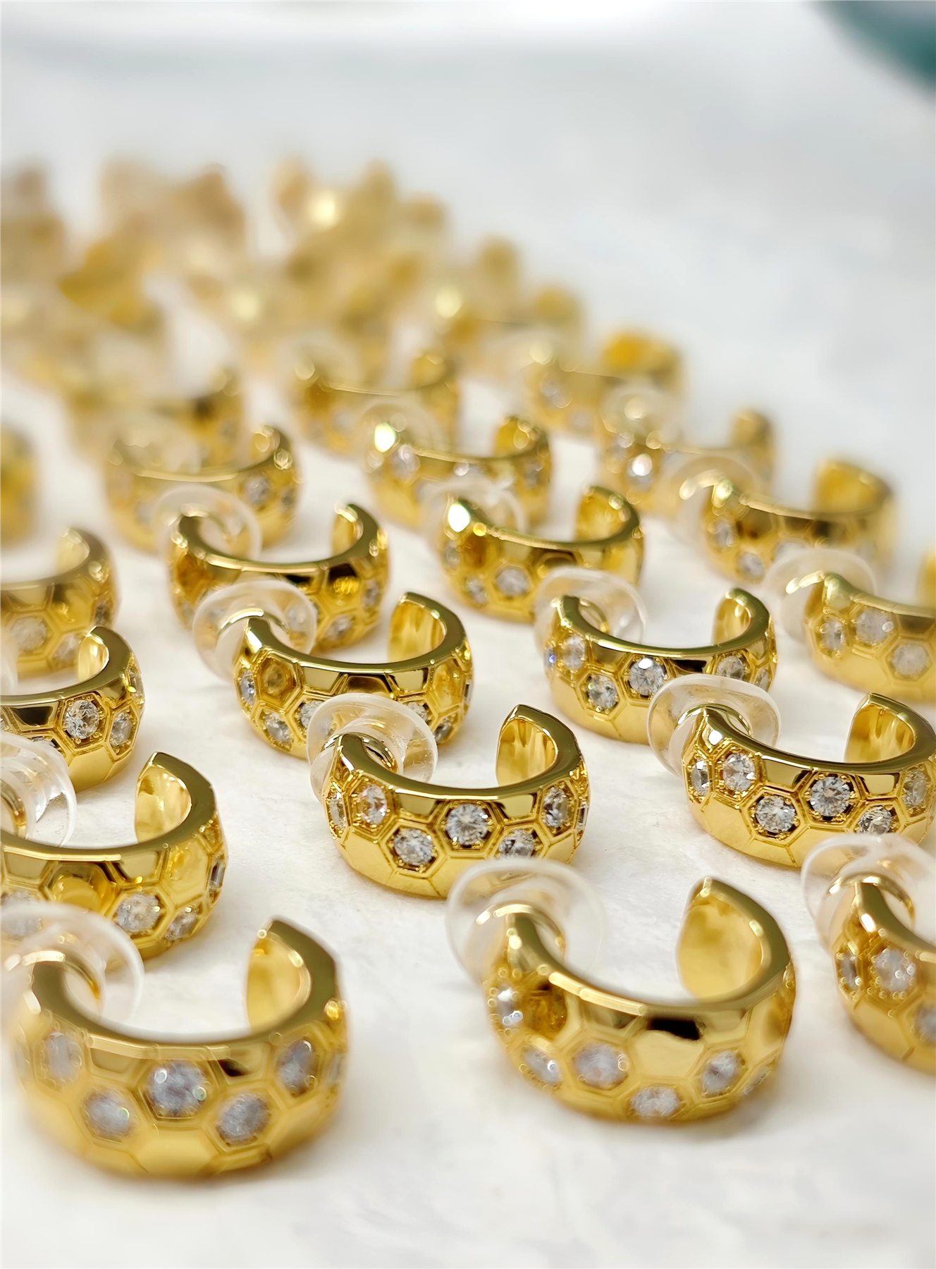 Batch of gold-color crystal ear cuffs arranged for production review